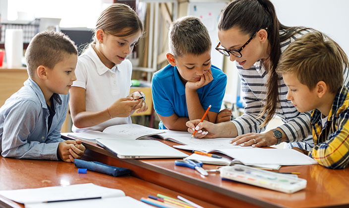 A Comparative Study of Self-Supervision and the Self-Efficacy of Iranian EFL Teachers and Those of Intermediate Adult Learners 4 elementary school teacher helping students with lesson 704x421 1